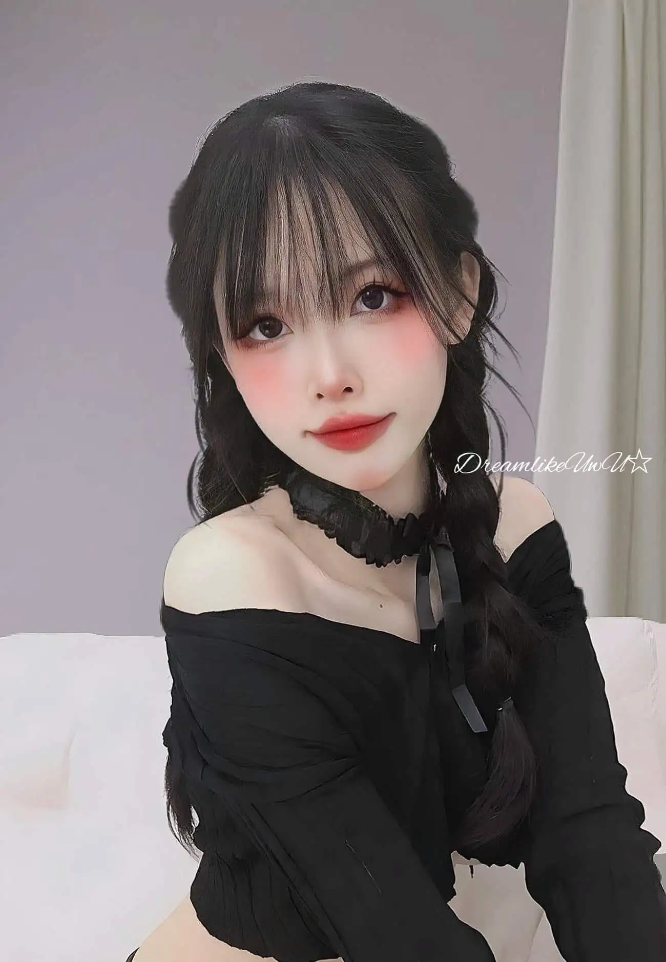 DreamlikeUwU黑色长发编双辫,穿黑色一字肩上衣与黑色蕾丝颈饰的室内半身像