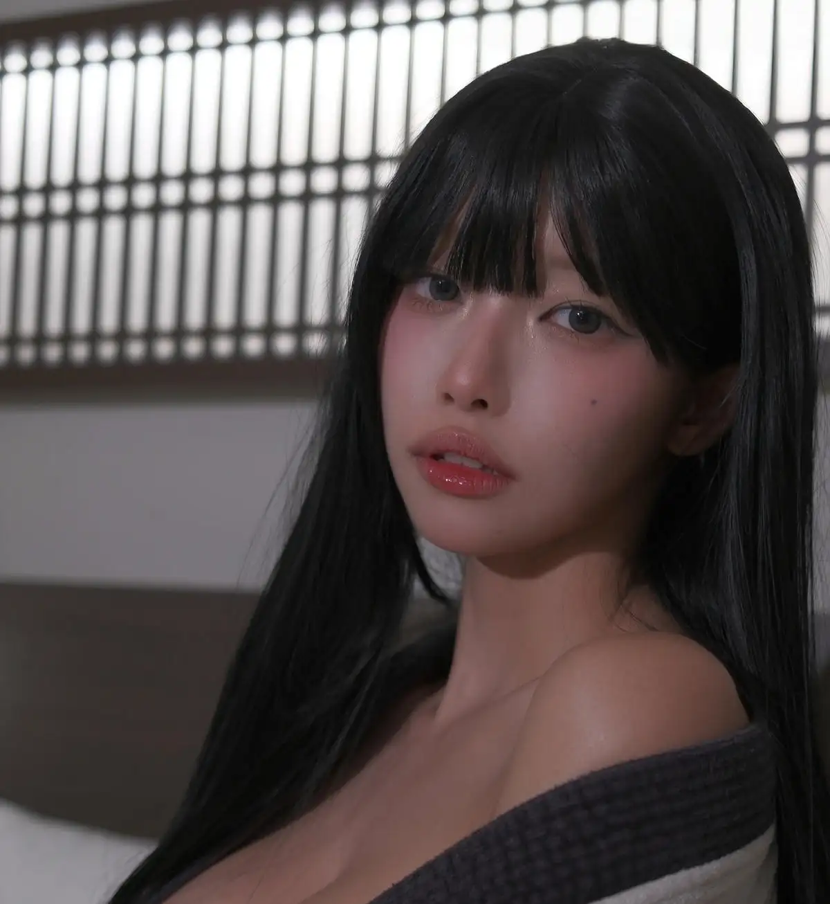 九曲Jean黑色长发齐刘海的近景,深灰落肩针织,背景是和风木格栅窗