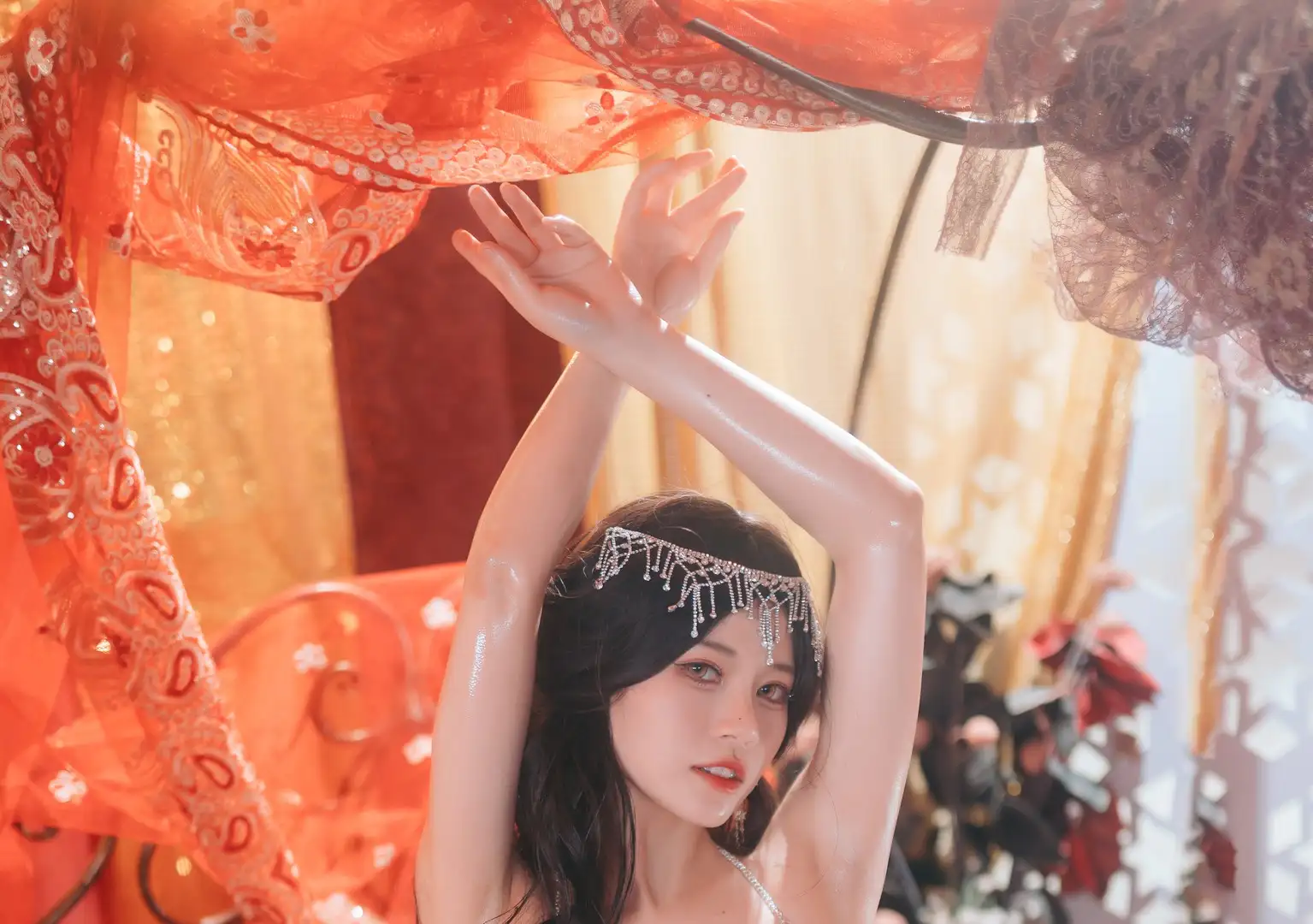 千反田鹿子戴银色额饰双臂上举的近景,背景是橙红色纱幔与暖光