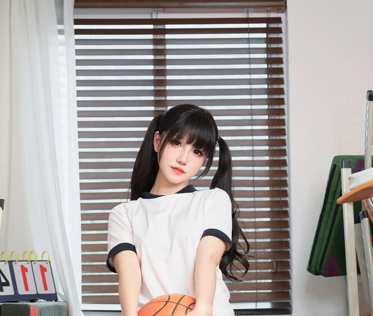 阿薰黑色双马尾扎起,穿白色黑边体操服在室内怀抱一只橙色篮球