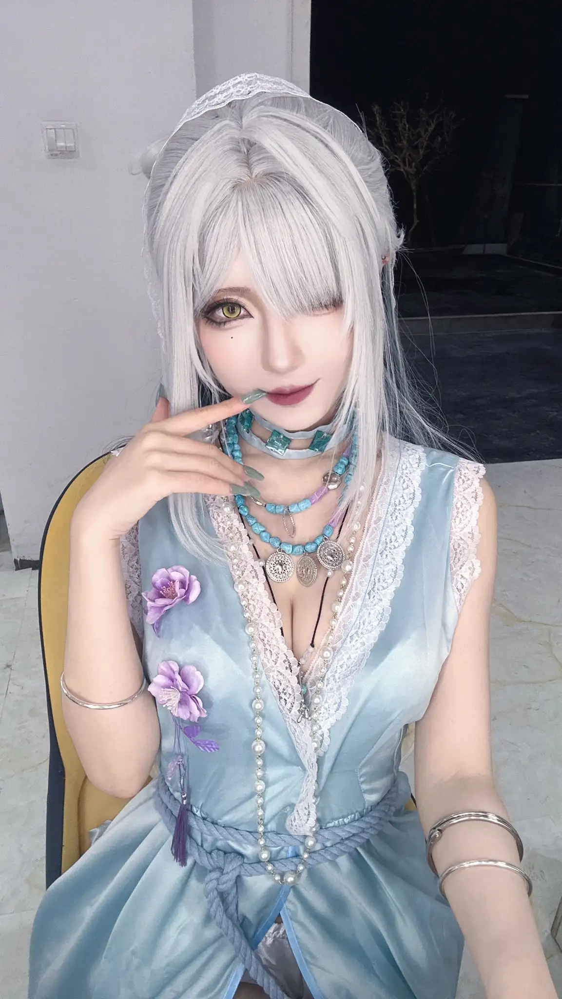弥音音白色长直假发与金黄瞳色,穿浅蓝无袖缎面裙配紫花与多层项链,坐姿手指轻触下唇 弥音音白色长直假发与金黄瞳色,穿浅蓝无袖缎面裙配紫花与多层项链,坐姿手指轻触下唇