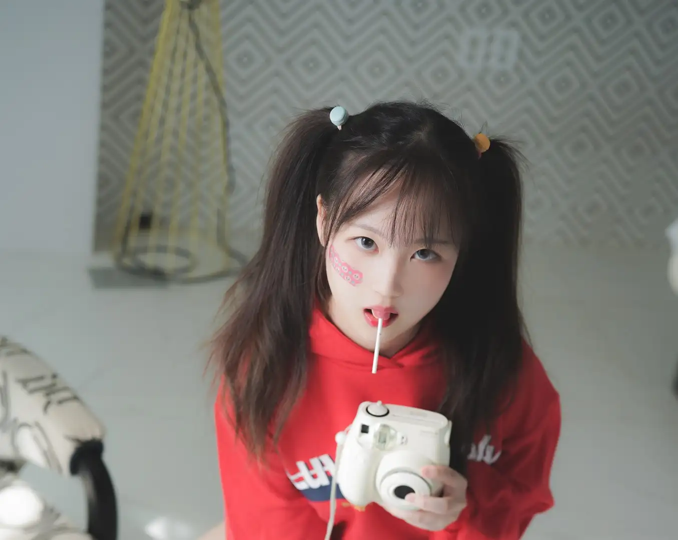 双马尾红色卫衣,手持拍立得相机。