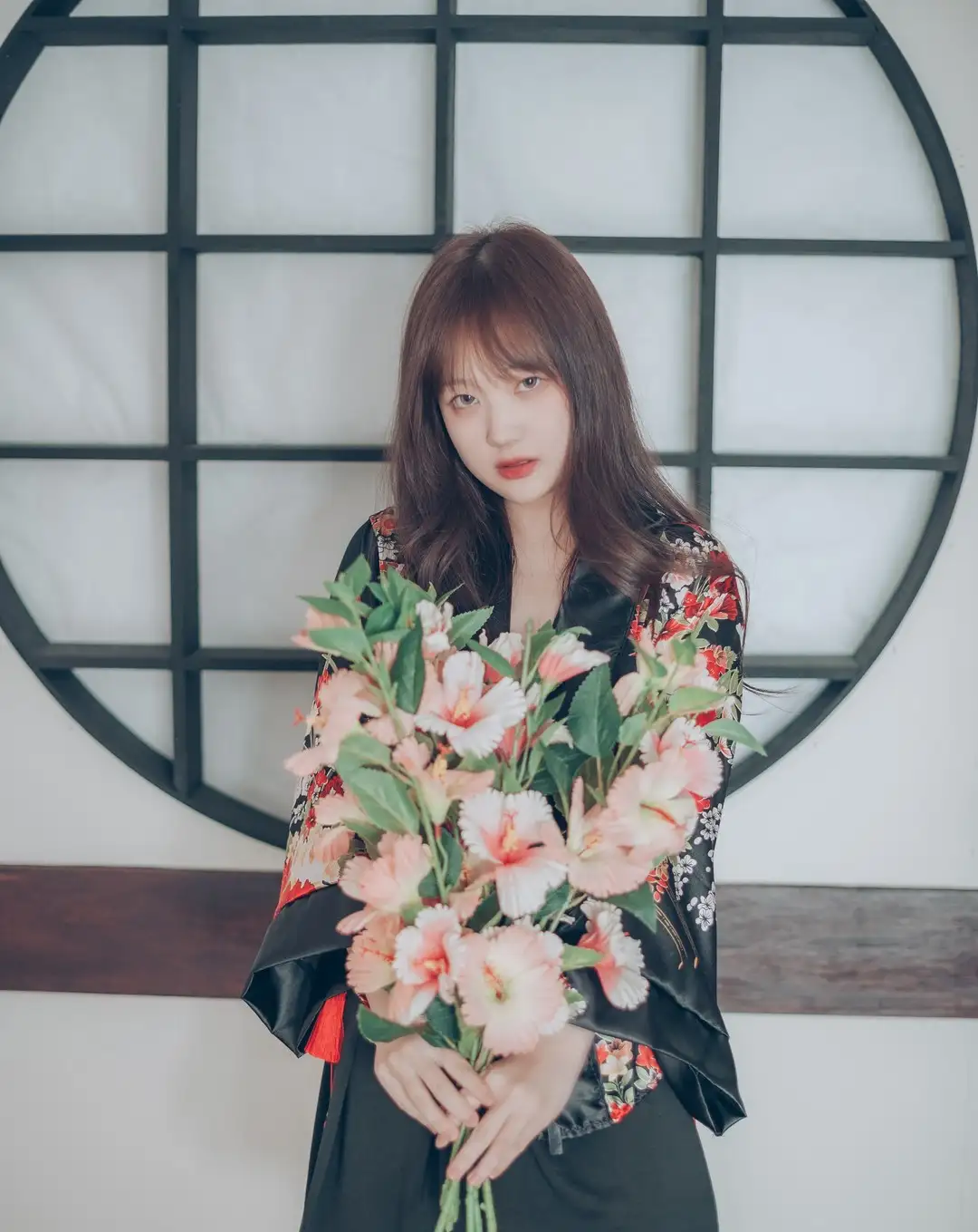 黑底花纹袍服,圆窗前手捧花束。